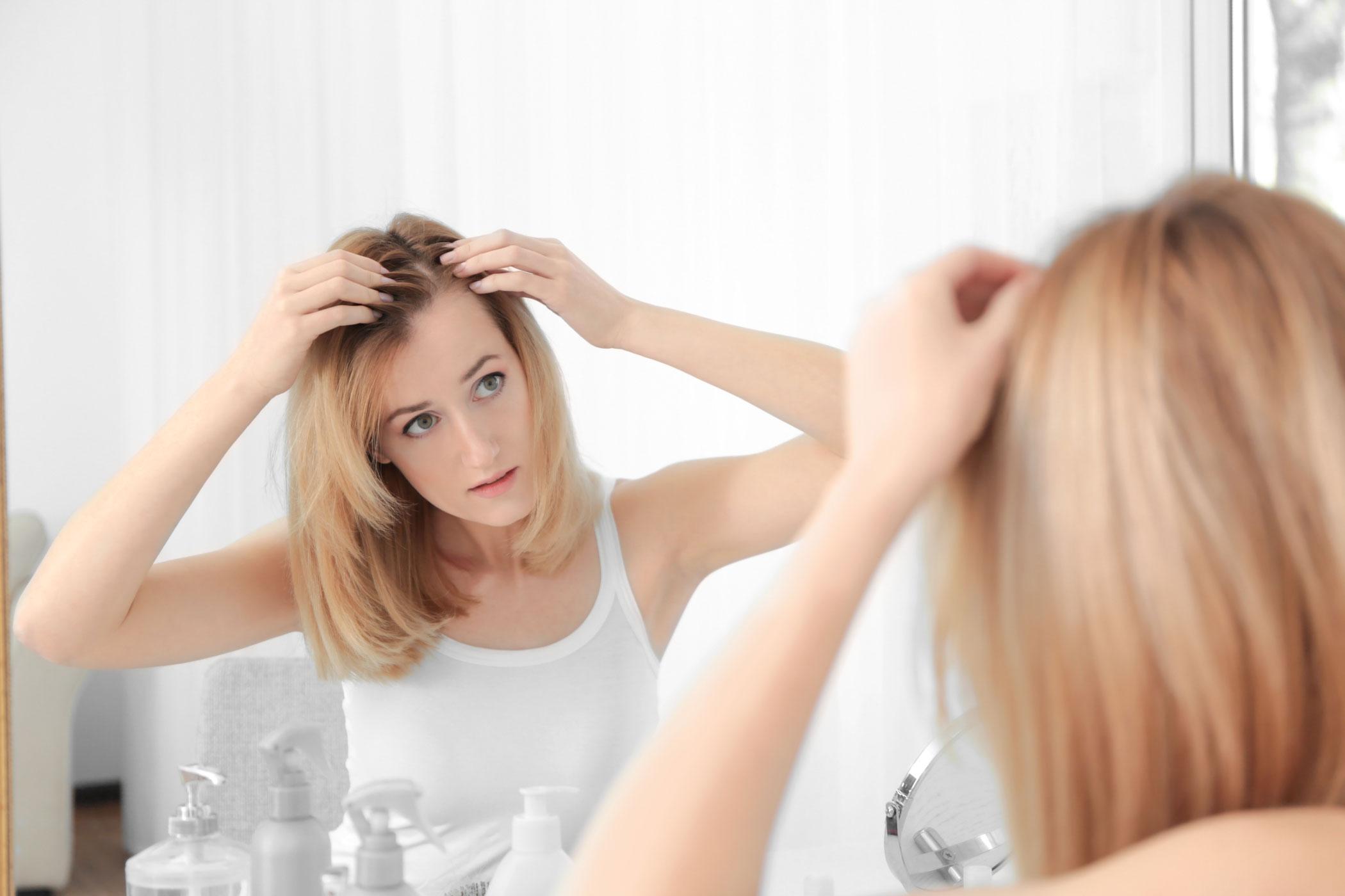 Woman checking her thinning hair in the mirror