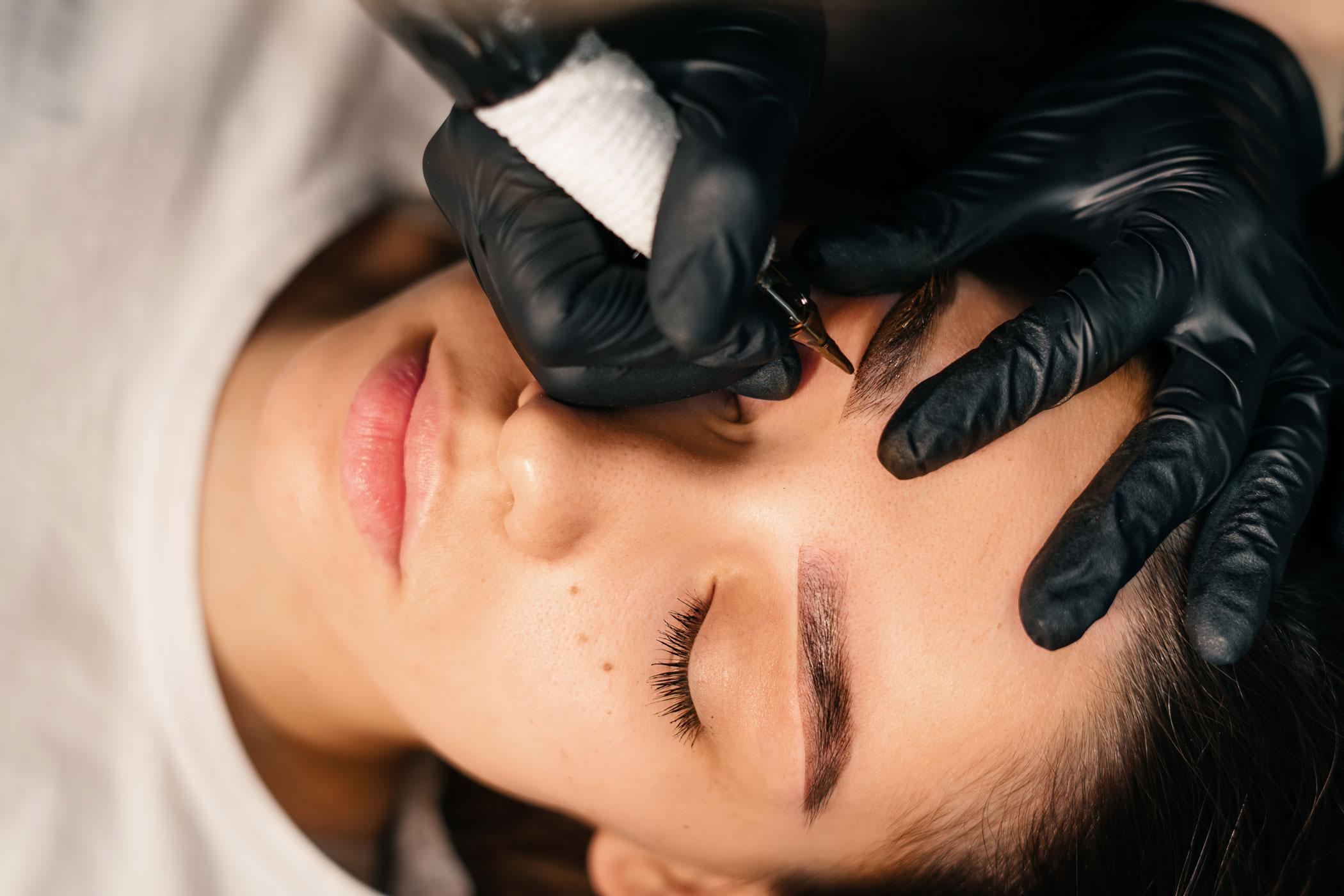 Artist tattooing a client's eyebrows