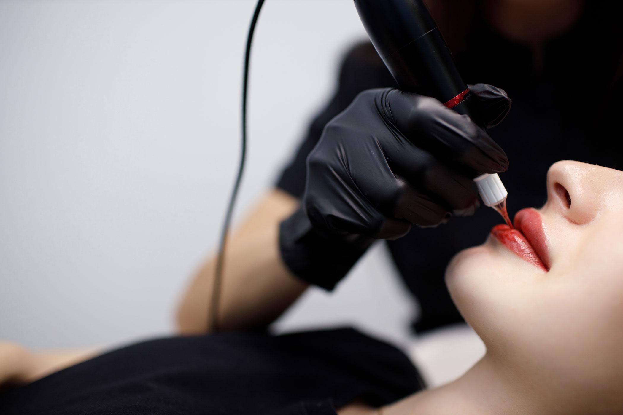 Artist applying lip color with a permanent makeup machine