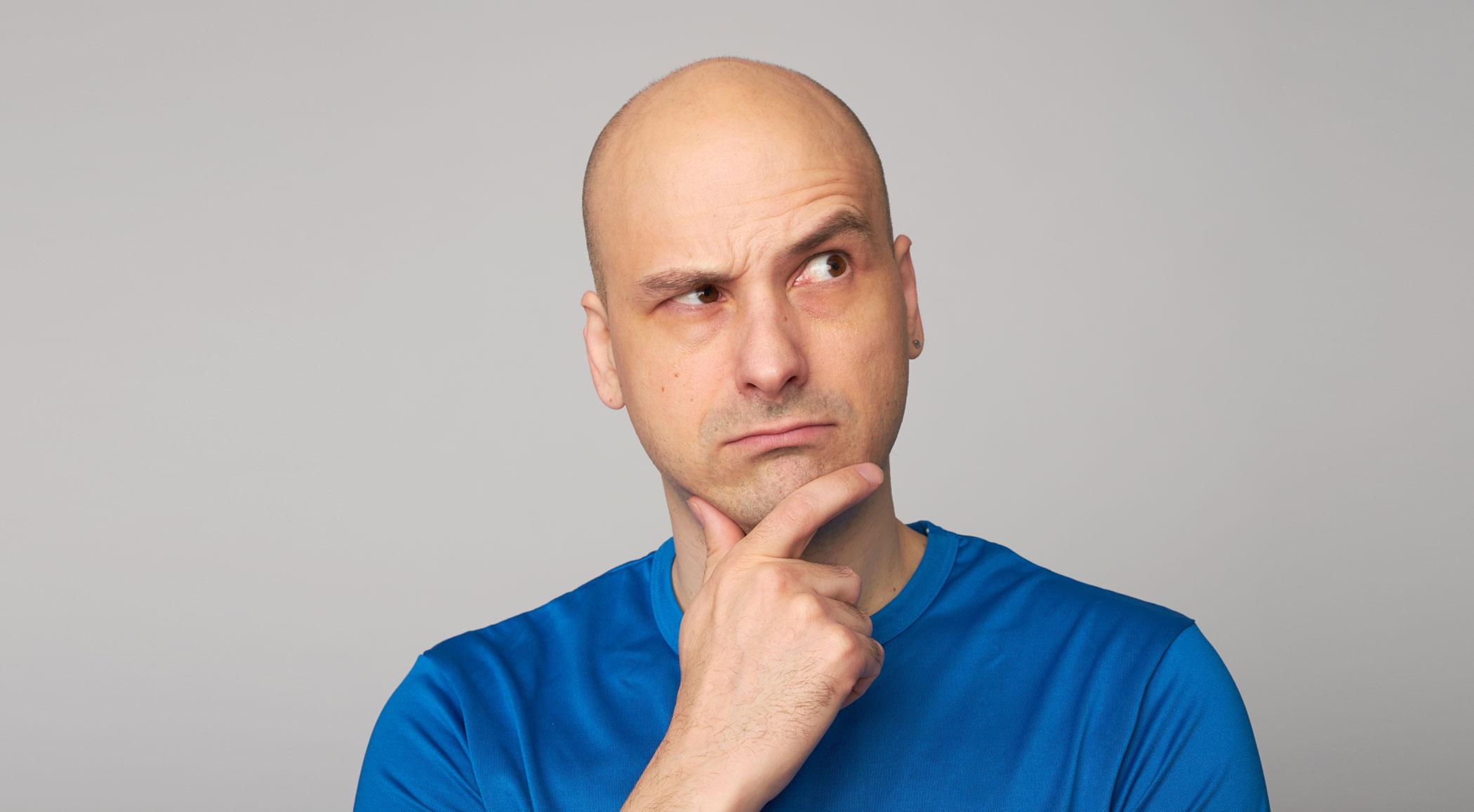 Man with a shaved head thinking about a question